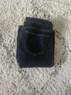 Mörkblå skinny jeans med kontrastsömmar - Snygga mörkblå skinny jeans med klassiska kontrastsömmar och femficksmodell. Jeansen har en smal passform och är tillverkade i ett stretchigt denimtyg som sitter tajt längs benen. Perfekta för en trendig och stilren look.