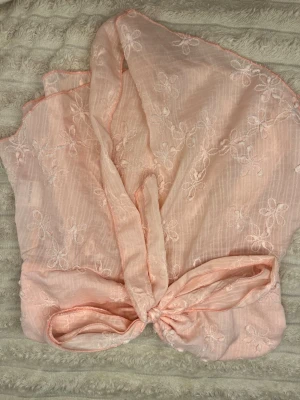 Ljusrosa omlottopp med broderade blommor - Superfin ljusrosa omlottopp med broderade blommor och knyt framtill. Jag vet inte varför bilderna blev upp och ner, har använts en gång i tre timmar annars helt orörd men inte min stil längre😛❤️