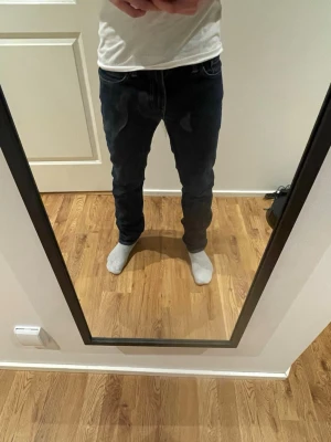 Mörkblå slim jeans - Snygga mörkblå jeans med klassisk femficksdesign. Jeansen har kontrastsömmar och silverfärgade nitar. Tillverkade i slitstark denim som ger en tidlös look. Perfekta för dig som gillar enkel och clean stil. W30/l34 