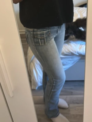 Ljusblå raka jeans med fickdetaljer - Säljer ett par ljusblå jeans med raka ben och snygga fickdetaljer bak. Jeansen har klassisk femficksmodell och är i ett mjukt denimtyg som sitter skönt. Perfekta till vardagslooken och passar till det mesta i garderoben.