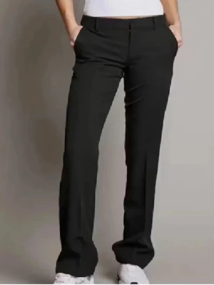 Svarta kostymbyxor från Bik Bok - Snygga svarta kostymbyxor med raka ben och pressveck. Byxorna har fickor i sidorna och hällor för skärp. Perfekta för en clean och stilren look. Materialet ser ut att vara en mjuk och följsam mix, troligen polyester eller viskos.