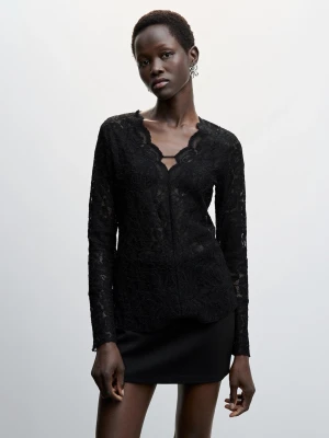 Svart spetsblus med v-ringning från mango - Elegant svart blus i spets från mango med v-ringning och vågformad kant. Blusen har långärmade ärmar och är tillverkad i ett genombrutet spetsmaterial som ger en lyxig känsla. Perfekt att styla med kjol eller byxor för en trendig look.