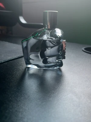 Diesel Only The Brave parfym - Cool parfym från Diesel i en unik flaska formad som en knytnäve. Flaskan är genomskinlig med en lätt blå ton och har ett silverfärgat lock. Perfekt för dig som gillar statement-detaljer på hyllan. ca 40 ml kvar