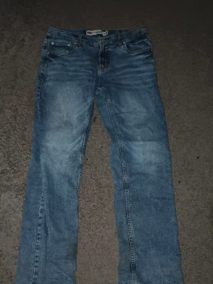 Levi's 551Z blå raka jeans - Säljer ett par klassiska blå Levi's 551Z AUTHENTIC STRAIGHT jeans med raka ben och fem fickor. Jeansen har en snygg tvättad look och detaljer i silverfärgade nitar. Perfekta för en avslappnad och tidlös stil. Nypris 900kr