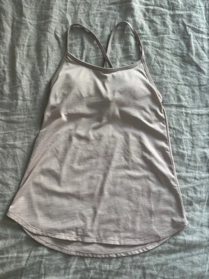 Ljusrosa yogalinne - Säljer ett ljusrosa linne från Manduka med tunna axelband. Toppen har inbyggd bh och är tillverkad i ett stretchigt, snabbtorkande material som passar perfekt för gym eller yoga.