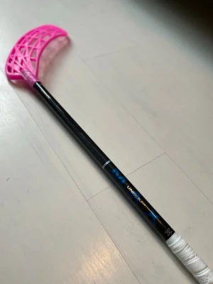 Unihoc innebandyklubba svart/rosa - Säljer en innebandyklubba från Unihoc med svart skaft och ett rosa blad. Skaftet har blå detaljer och greppet är vitt. Perfekt för dig som vill ha en snygg och lätt klubba till träning eller match.