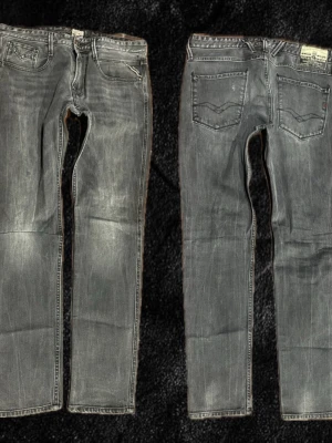 Grå Replay Ambass Jeans - W34 (sitter som W33) L32. Säljer ett par gråa Replay jeans med raka ben och klassisk femficksmodell. Jeansen har slitna detaljer och ljus tvätt för en cool, avslappnad look. Bakfickorna har snygga sömmar och Replay-märke på linningen. Perfekta för dig som gillar streetwear.