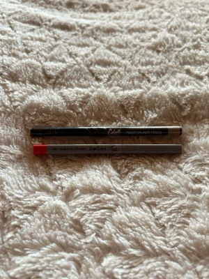 Två läppennor i olika färger - Säljer två läppennor: en från the makeup library i grått med röd topp och en från Chatte i svart. Perfekta för att definiera och forma läpparna. Twist-funktion på den svarta pennan. (Endast testade)! 💓🌸