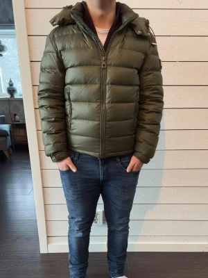 Olivgrön Bvaldi jacka - En olivgrön Bvaldi dun jacka som är riktigt skön med en justerbar luva och tre fickor. Denna jacka har jag nu haft i 1 år och är en av dom skönare jackorna jag haft som klarar av kallare perioder som är perfekt för dig som söker en snygg och skön jacka som ska hålla dig varm. Den är använt i gott skick inga skador eller missfärgningar osv. Jag kan tillägga att jag är 167cm lång så att man får en bättre uppfattning. Pris kan absolut diskuteras och det är bara att skriva om man undrar något mer👍