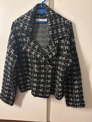 Svartvit rutig kappa från ZARA - Trendig svartvit kappa från ZARA med rutigt mönster och dubbelknäppning framtill. Kortare modell med breda slag och långa ärmar. Tjockare tyg som ger en snygg struktur och modern look. Perfekt för dig som vill sticka ut med stil. Orginalpris:899kr