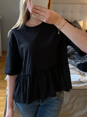 Svart topp med volang från Gina Tricot - Säljer en svart T-shirt topp med bred volang från Gina Tricot i storlek S. Super söt och passar super till våren. Super bra skick, använd kanske två gånger. Hör gärna av dig vid frågor💗