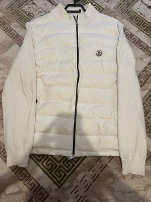 Vit pufferjacka från Moncler - Storlek M säljer på grund av har  köpt en annan Snygg vit  Cardigan från  Moncler Perfekt för kalla dagar när du vill hålla stilen. Klassisk passform och ribbad krage för extra komfort.