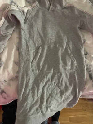 Grå hoodie från Gant med logga - Snygg grå hoodie från Gant med huva och magficka. Ärmarna har en vit rand med Gant-logga längs hela sidan, hoddie/ klänning väldigt praktisk storlek XS