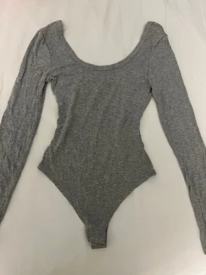 Grå långärmad body - En stilren grå body med urringning💕 Endast använd en gång 