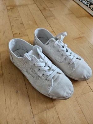 Vita spetsdetaljerade sneakers - Snygga vita tunna sommar sneakers med spets från Anna Field. Skorna har vita snören och detaljer i spets på sidorna. De är använda flera gånger och är därför i helt okej skick, men går fortfarande att använda helt galant. Kolla bilderna för smuts. De går säkert att tvättas på något sätt men passar inte mig längre. Ursprungspriset är runt 230 kr.