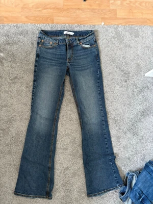 Blå bootcut jeans från Junkyard - Jeansen har en lätt tvättad look och är tillverkade i denim med en skön passform. Perfekta för dig som gillar en avslappnad men trendig stil. Nypris är 399. 