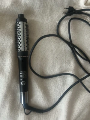 Svart varmluftsborste från Babyliss - Elektrisk varmluftsborste från Babyliss i svart och silver med rund borste och borststrån runt hela cylindern. Perfekt för att styla och forma håret med volym. Utrustad med sladd och strömbrytare på handtaget. Har aldrig använt. 