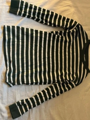 Randig långärmad topp från Cubus för barn  - Grön och vit randig långärmad topp från C. Klassisk rund halsringning och mjukt material i bomull. Perfekt för en avslappnad och stilren look. Passar dig som gillar enkel men snygg design.