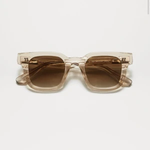 Beige solglasögon från CHIMI - Snygga solglasögon från CHIMI med transparent beige båge och fyrkantig form. Glasen är tonade i brunt och bågarna är tillverkade i syntetmaterial. Perfekt accessoar för att lyfta din stil.