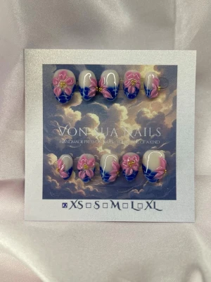 Yemoja (XS);ExtraShortAlmond  - Handgjorda press-on naglar i extra kort mandel form. Naglarna har en nude bas med blå tippar och dekoreras med 3D-blommor i rosa och gult. Perfekt för dig som vill ha en unik och färgstark look. XS: 14 mm, 11 mm, 11,5 mm, 10 mm, 8 mm