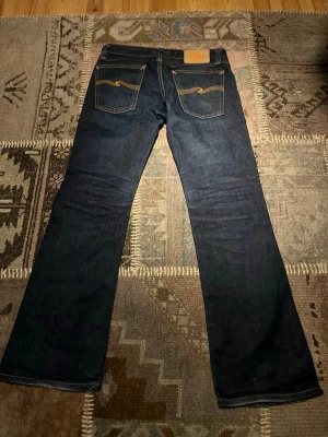 Nudie Jeans Bootcut Eddy W29 - Säljer ett par Nudie Bootcut Eddy i raw denim. Utgången modell som är svår att få tag på idag, känd för sin klassiska flare. Jeansen är i bra skick och har en påbörjad naturlig patina, vilket ger fina förutsättningar för personliga fades.                                                                                 Storlek: W29 / L30  Skickas inom 12 timmar. Meddela vid frågor eller önskemål om fler bilder. 
