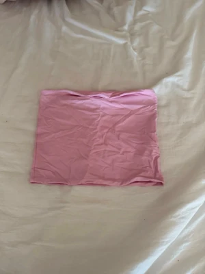Rosa tubtop i stretchigt material - Säljer en enkel och snygg rosa tubtop i stretchigt material. Perfekt att matcha med jeans eller kjol för en trendig look. Toppen är enfärgad och har en mjuk känsla mot huden.