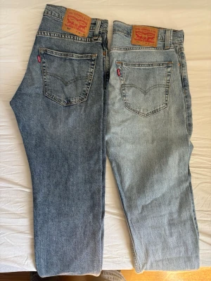 Levi's ljusblå raka jeans - Klassiska ljusblå jeans från Levi's med raka ben och femficksmodell. Jeansen har den ikoniska röda Levi's-lappen på bakfickan och patch i läder bak i midjan. Perfekta för en avslappnad och trendig look. Jag tror nya kostar runt 700kr st. 200 kr styck