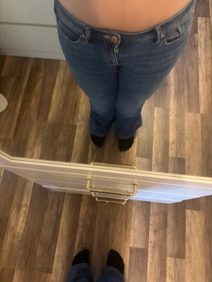 Blå bootcut jeans från veromoda - Säljer ett par klassiska blå bootcut jeans från veromoda med femficksdesign och läderpatch bak i midjan. Jeansen har normal midja och är tillverkade i denim med en snygg tvätt. Perfekta för dig som gillar en tidlös och avslappnad look. Längd 30. Stretchiga. 