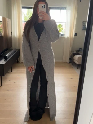 Lång grå stickad kofta med knappar - Säljer den supermysiga långa gråa stickade koftan/klänningen från Gina tricot. Den är använd en del men fortfarande i väldigt fint skick!✨