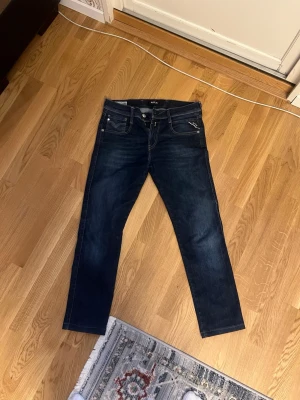 Mörkblå slim jeans från replay - Snygga mörkblå slim fit jeans från Replay  med klassisk femficksdesign och kontrastsömmar. Jeansen har en diskret logga på bakfickan och är tillverkade i ett mjukt denimtyg som sitter skönt hela dagen. Modell: Anbass