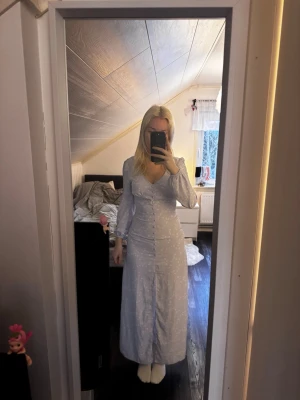 Lila långklänning - Lila blommig lånklänning med knappar framtill och dragkedja i ryggen (knappar är inte funktionella). Superfin till mösspåtagning eller midsommar, liknar adoore!                                                             Köptes begagnad🩷