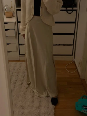 Beige långkjol i satin - Säljer en beige långkjol med mjukt fall och lätt glansig satinlook. Kjolen har en enkel och stilren design som passar perfekt till både stickade tröjor och toppar. Superskön och flowy känsla! Aldrig använd storlek xxs
