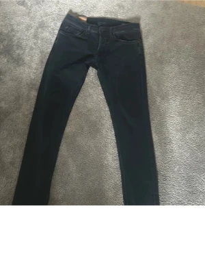 Mörkblå skinny jeans från Diesel - Säljer ett par mörkblå skinny jeans från Diesel med klassisk femficksdesign och diskret D-detalj på bakfickan. Jeansen har en smal passform och är tillverkade i stretchigt denimtyg för extra komfort. Perfekta för en trendig och avslappnad look.