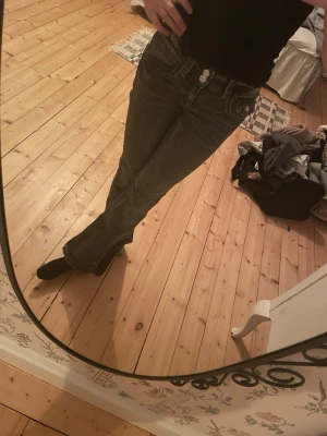 Lågmidjade bootcut jeans - Säljer ett par mörkgrå bootcut jeans med låg midja och dubbla knappar fram. De är använda ganska mycket men är ändå i jätte bra skick (inga slitningar vid hälarna osv) säljer då de håller på att bli för små 💕