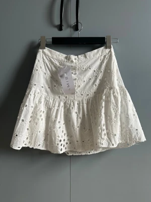 Ny! Vit broderad kjol från AMISU strl 36 - Ny med lapp! Supersöt vit kjol från Amisu med broderade detaljer och volang. Kjolen har ett luftigt och romantiskt uttryck med hålmönster och är tillverkad i bomull. Perfekt för dig som gillar en feminin och somrig stil.