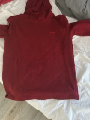 Mörkröd hoodie med huva - En enkel och stilren mörkröd hoodie med huva. Hoodien har lång ärm och är tillverkad i ett mjukt, tunt material som känns skönt mot huden. Passar perfekt för en avslappnad look och är lätt att matcha med andra plagg. OBS LITEN I STORLEK