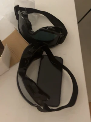 2st Svarta skid glassögon med bred rem - Säljer ett par svarta och svart med spegelglas skidglasögon med bred elastisk rem. Glasögonen har en sportig look med tonade linser och passar perfekt för utomhusaktiviteter som skidor eller som accessoar.  sitter bekvämt runt huvudet. Du får båda för 700 kr 