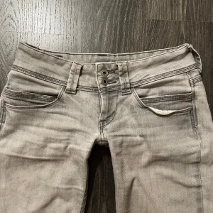 Grå lågmidjade pepe jeans - Säljer dessa sjuukt snygga lågmidjade, ljusgrå pepe jeans i modell venus, straight. Säljer då de har blivit lite för stora. De har ett kryte i midjan så att man kan dra åt så att det passar en själv! De är W 29. Midjemått är 38 cm. Innerbenslängden är 76 cm och hela längden är 98 cm. Skriv privat vid fler frågor🤗💕
