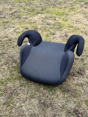 Svart bälteskudde för bil - En svart bälteskudde med armstöd, perfekt för att höja sittpositionen i bilen. Kudden har ett diskret rutmönster och är tillverkad i slitstarkt tyg med mjuka kanter för extra komfort. Passar barn som behöver extra höjd vid bilåkning.