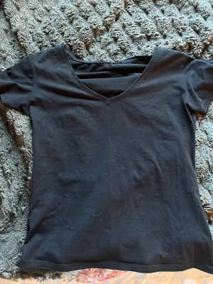 Svart v-ringad t-shirt - En enkel svart t-shirt med v-ringning och korta ärmar. Perfekt basplagg som passar till det mesta. Tillverkad i mjuk bomull för skön känsla hela dagen.