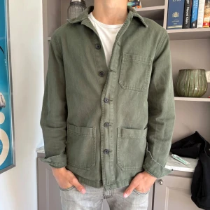 Grön overshirt - Riktigt go overshirt från 157 Roots. Den har tre stora fickor framtill och en lite sliten look. Perfekt nu till sommaren! Killen på bilden är 178 cm och väger 66 kg. Tveka inte på att fråga om du undrar något. 😁