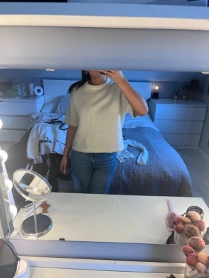 Ljusbeige stickad tröja Gina Tricot - Mysig ljusbeige stickad tröja från Gina Tricot med rund halsringning och korta ärmar. Tröjan har en rak, boxig passform och är tillverkad i ett mjukt, fluffigt material som känns skönt mot huden. Perfekt för lager på lager och enkel att styla.