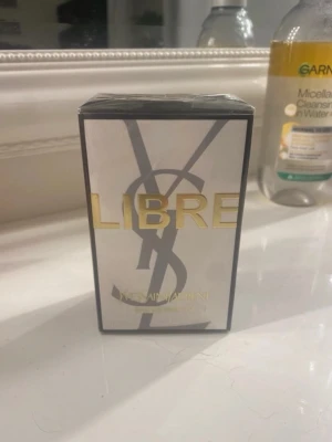 Yves Saint Laurent Libre parfym - Yves Saint Laurent Libre parfym i elegant rektangulär förpackning med svart och guld detaljer. Framsidan har stora bokstäver i guld och den ikoniska YSL-loggan. Perfekt för dig som gillar lyxiga och moderna dofter.30 ml, aldrig öppnad 
