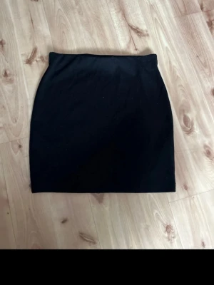 Svart kortkjol från Cubus - Enkel och stilren svart kortkjol från Cubus. Kjolen har en rak passform och är gjord i ett mjukt bomullsmaterial med stretch. Perfekt att matcha med en crop top eller oversized hoodie för en chill look.