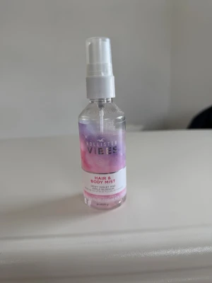 Hollister Vibes Hair & Body Mist - Fräsch hår- och kroppsmist från Hollister med doft av daggviolett och äppelblom. Flaskan är genomskinlig med lila och rosa detaljer och har en praktisk sprayfunktion. Perfekt för dig som vill ha en lätt och blommig doft i vardagen.