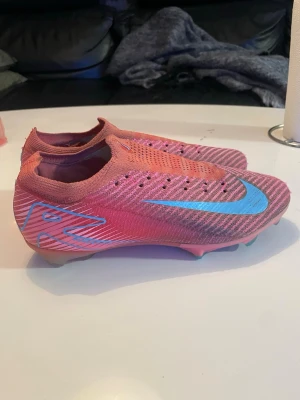 Nike Mercurial vapor 16 elite fg rosa/blå fotbollsskor - Nike elite fotbollsskor i okej skick. Har inga skosnören och ena innesulans färg har släppt lite som går att se på sista bilden. Skorna har också små skador som visas på bild 4 och 5. I övrigt är skorna i fint skick. Nypris ca 2-3 tusen