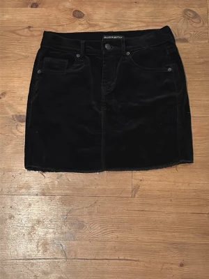 Svart manchesterkjol Brandy Melville  - Säljer en svart kort manchesterkjol från Brandy Melville. Kjolen har klassisk femficksdesign, knapp och dragkedja. Perfekt att styla med en stickad tröja. 