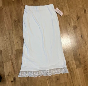 Vit ribbad spetskjol från Nelly - Oanvänd med prislappen kvar på! Supersnygg vit långkjol från Nelly med ribbad struktur och spetsdetalj längst ner.