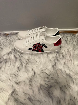 Gucci Ace  - Säljer ett par vita Gucci Ace sneakers med klassiska gröna och röda sidoband och en orm. Storlek 42 helt nya skriv vid eventuella frågor. Pris kan diskuteras.
