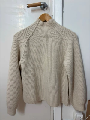 Beige ribbstickad polotröja - Säljer en beige ribbstickad tröja med liten låg hög krage och långa ärmar. Mjuk och super mysig skön stickad tröja, från H&M aldrig använd utan prislapp. Strl XS kan passa S också då den är väldigt bekväm 